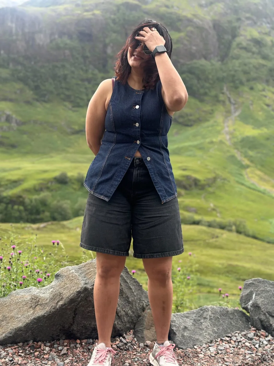 Bhagyashri standing on a rocky path in green hills